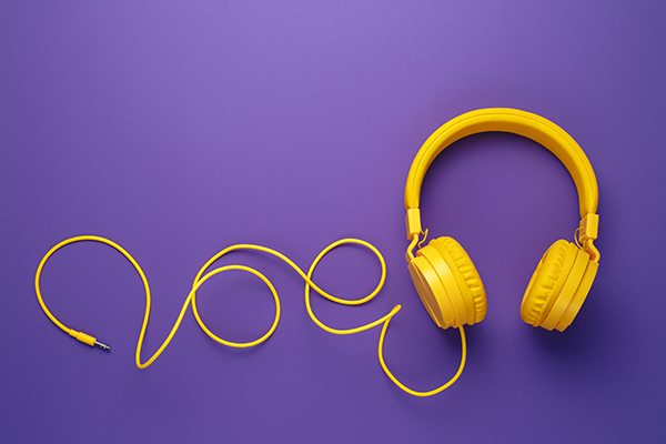 Yellow wired headphones on a purple background.