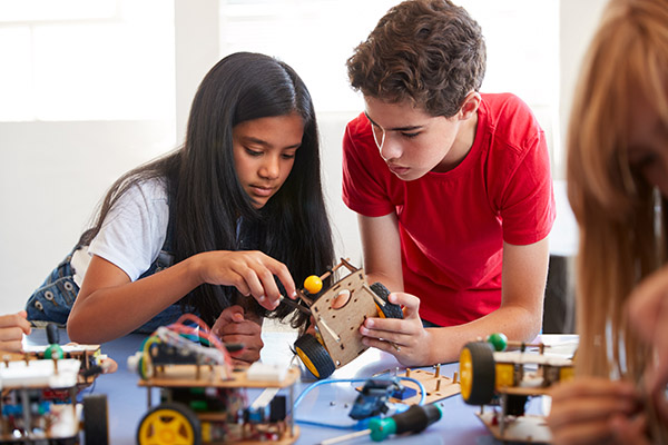 A girl and a boy work together on an electric vehicle project.